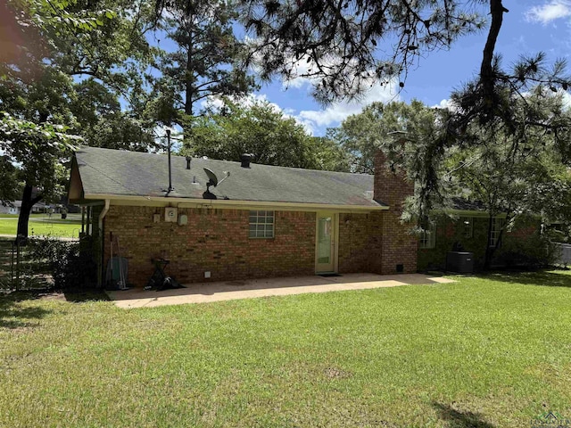 909 Stewart St, Atlanta, TX 75551 - back of property featuring a patio, a yard, a chimney, and brick siding