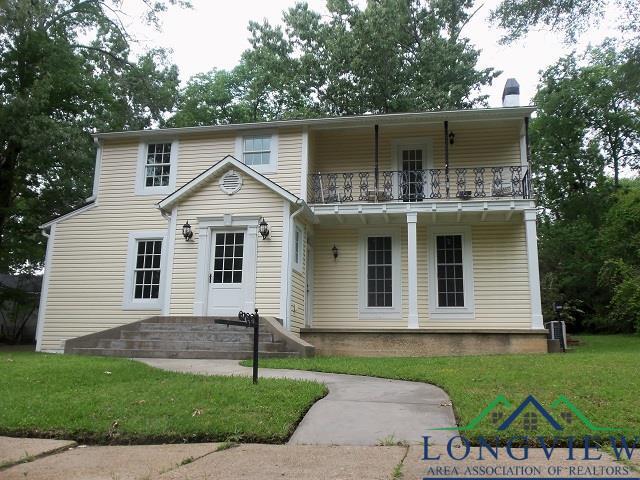 view of front facade featuring a balcony and a front yard