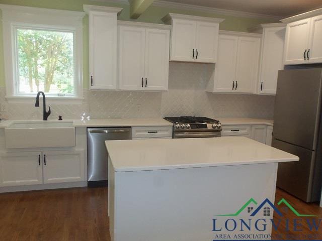 kitchen featuring white cabinets, sink, appliances with stainless steel finishes, tasteful backsplash, and a kitchen island