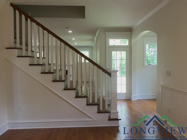 stairway featuring wood-type flooring and crown molding