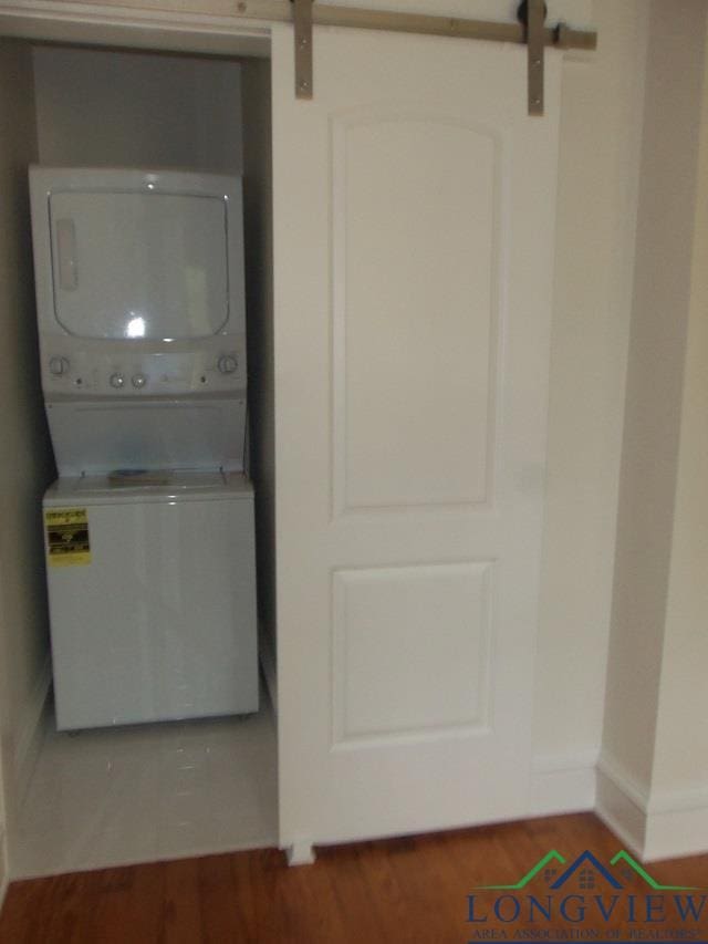 laundry room featuring a barn door and stacked washing maching and dryer