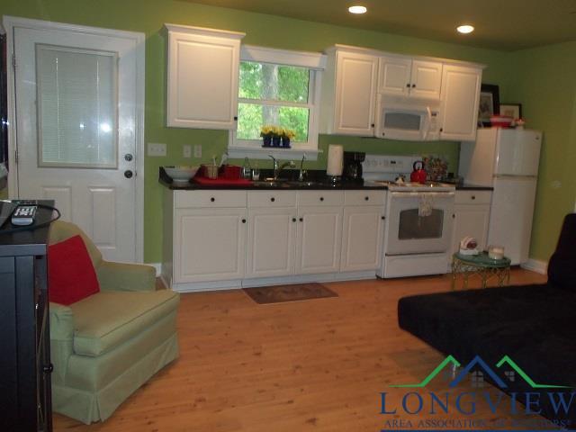 kitchen with white cabinets, light hardwood / wood-style floors, white appliances, and sink