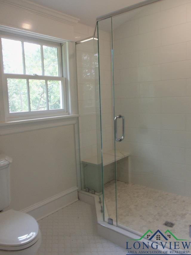 bathroom featuring crown molding, a shower with door, tile patterned flooring, and toilet