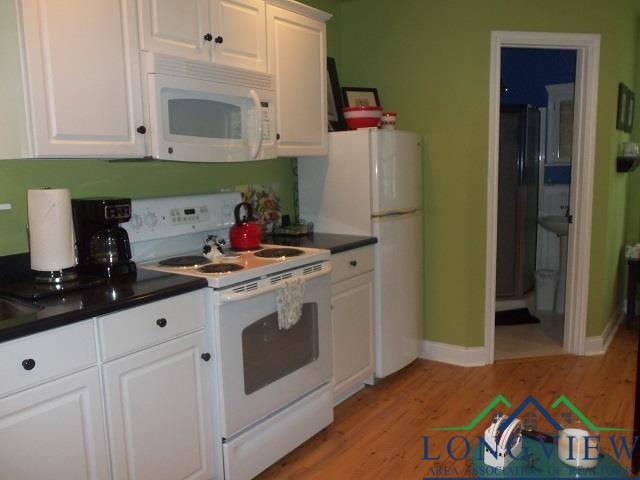 kitchen featuring white cabinets, light wood-type flooring, and white appliances