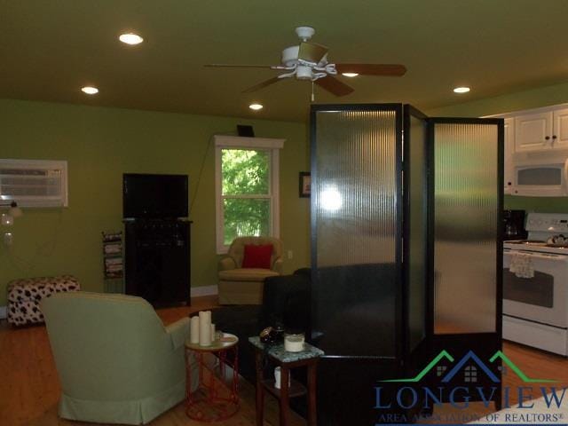 kitchen featuring a wall mounted air conditioner, white appliances, white cabinets, hardwood / wood-style flooring, and ceiling fan