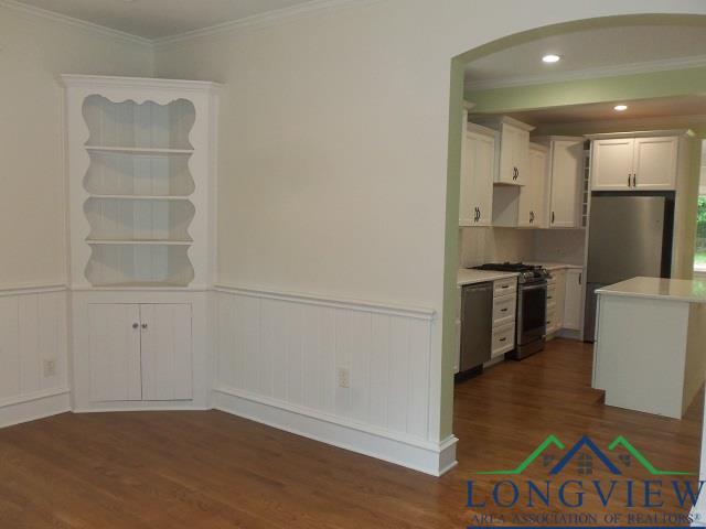 kitchen with white cabinetry, ornamental molding, dark hardwood / wood-style floors, and appliances with stainless steel finishes