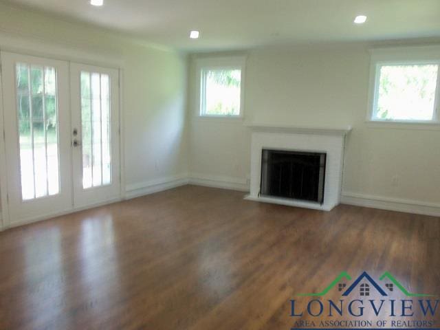 unfurnished living room featuring french doors, dark wood-type flooring, and plenty of natural light