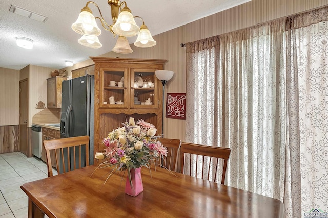 dining space featuring a textured ceiling, wallpapered walls, light tile patterned floors, an inviting chandelier, and visible vents