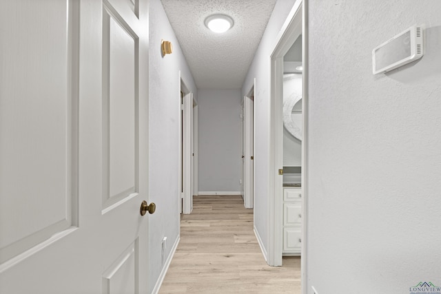 corridor with light hardwood / wood-style flooring and a textured ceiling