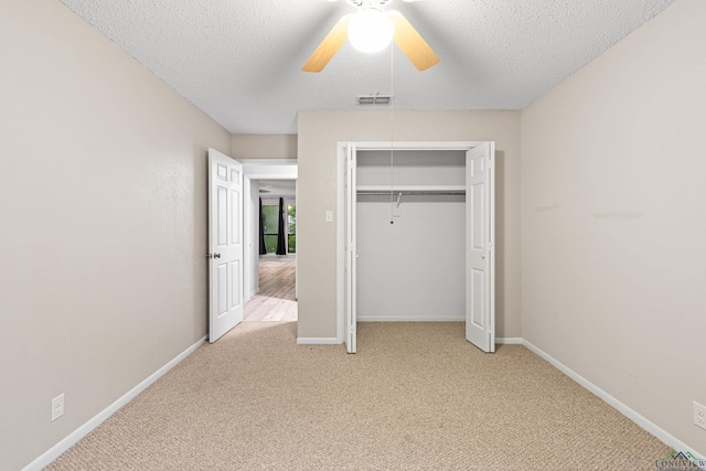 unfurnished bedroom with ceiling fan, a closet, light carpet, and a textured ceiling