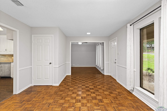 hallway with dark parquet flooring and a textured ceiling