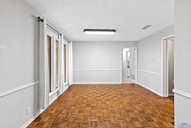 spare room featuring a textured ceiling and dark parquet floors