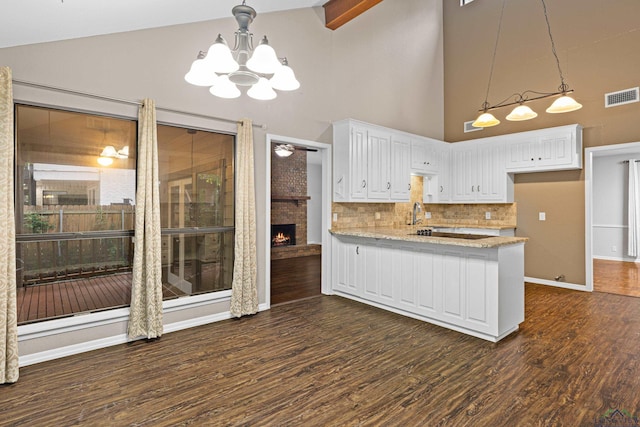 kitchen featuring light stone countertops, hanging light fixtures, a notable chandelier, backsplash, and white cabinets