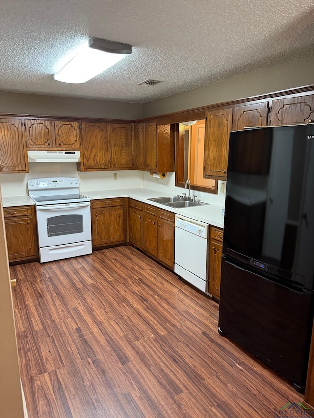 206 Syble Ln, Longview, TX 75605 - kitchen featuring white appliances, under cabinet range hood, brown cabinetry, a textured ceiling, and light countertops