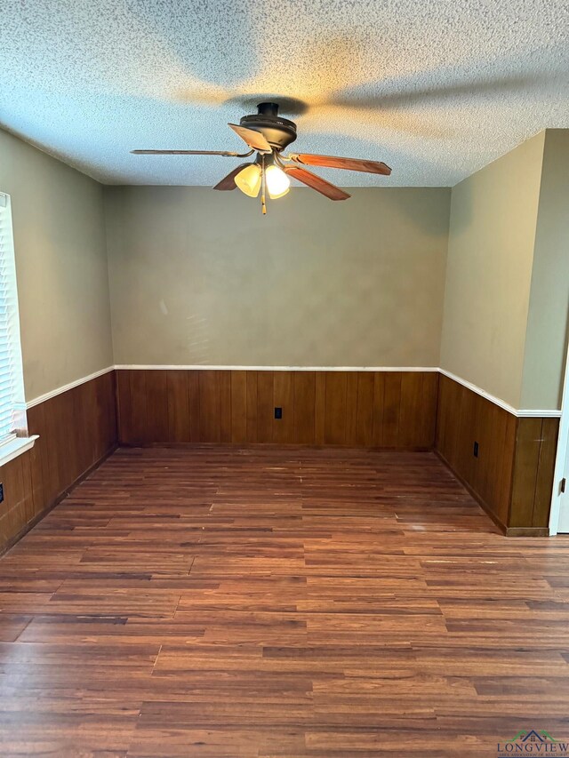 206 Syble Ln, Longview, TX 75605 - unfurnished room with ceiling fan, wood finished floors, a wainscoted wall, a textured ceiling, and wood walls
