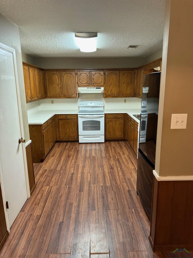 206 Syble Ln, Longview, TX 75605 - kitchen featuring white range with electric stovetop, under cabinet range hood, fridge, brown cabinetry, and a textured ceiling