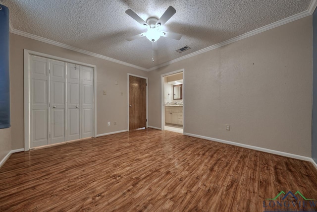 unfurnished bedroom with hardwood / wood-style floors, ornamental molding, a closet, and a textured ceiling