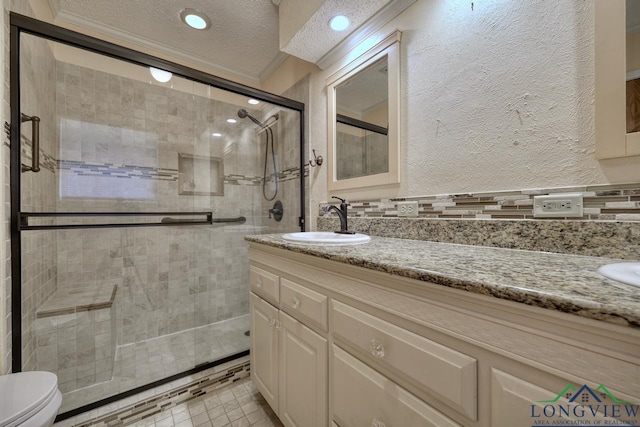 bathroom with a shower with shower door, vanity, ornamental molding, toilet, and a textured ceiling