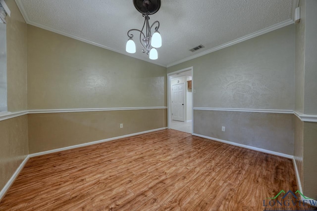 spare room with crown molding, a chandelier, a textured ceiling, and light hardwood / wood-style floors