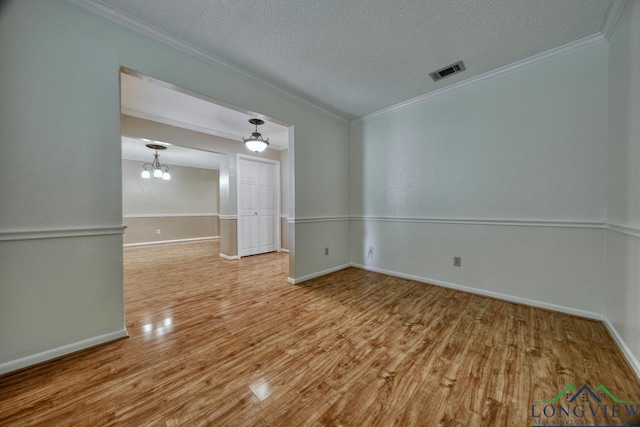 empty room featuring hardwood / wood-style flooring, crown molding, an inviting chandelier, and a textured ceiling