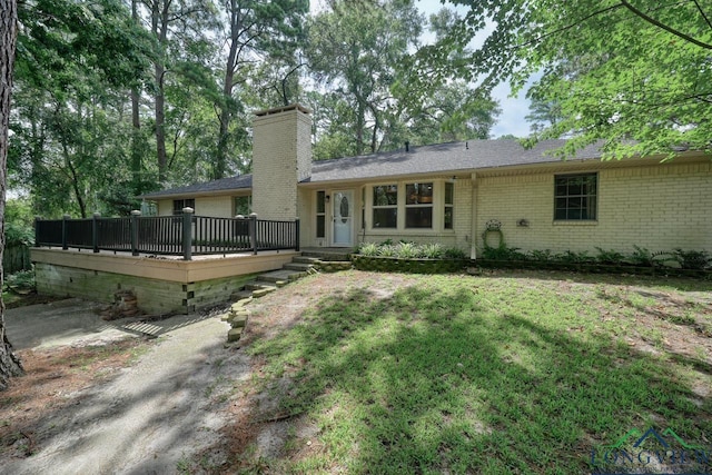 back of property featuring a wooden deck and a lawn