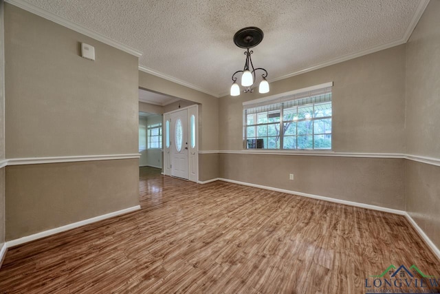 empty room featuring crown molding, hardwood / wood-style floors, and a textured ceiling