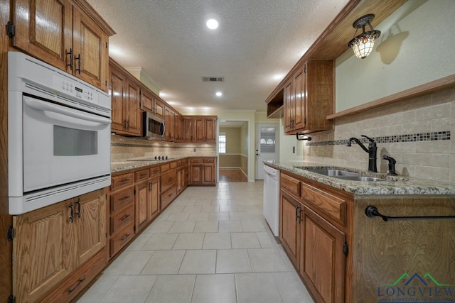 kitchen with light stone counters, white appliances, sink, and tasteful backsplash