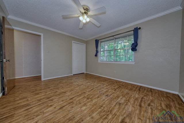 unfurnished bedroom featuring wood-type flooring, a textured ceiling, ornamental molding, a closet, and ceiling fan