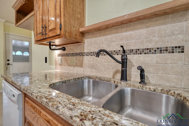 kitchen with white dishwasher, light stone countertops, sink, and backsplash