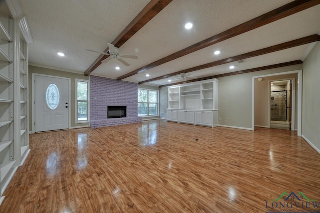 unfurnished living room featuring ceiling fan, a fireplace, a textured ceiling, and light wood-type flooring