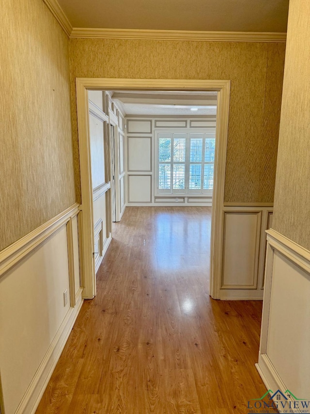 hall with light wood-type flooring and ornamental molding