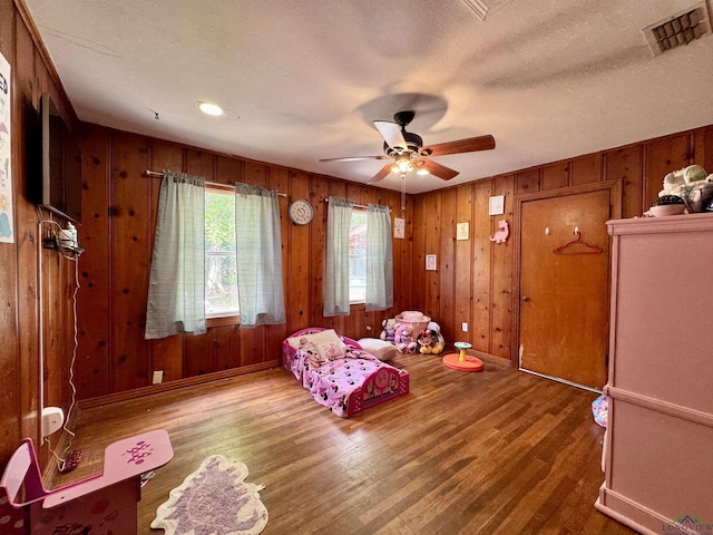 1009 Willow Springs Dr, Longview, TX 75604 - living room with wood finished floors, ceiling fan, wooden walls, and a textured ceiling