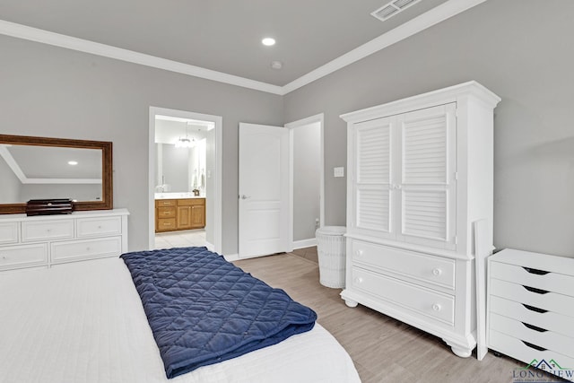 bedroom featuring light hardwood / wood-style flooring, crown molding, and ensuite bath