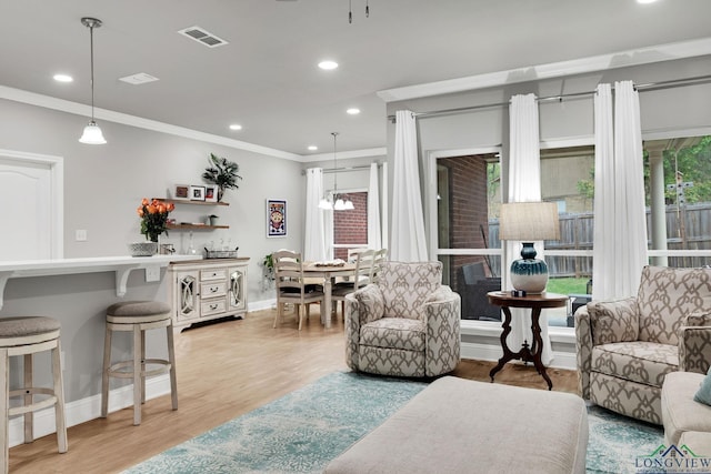 living room with crown molding, light hardwood / wood-style flooring, and an inviting chandelier