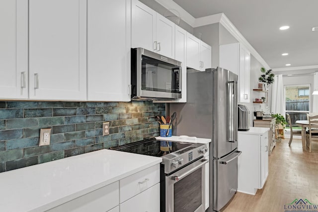 kitchen featuring white cabinetry, light hardwood / wood-style flooring, decorative backsplash, appliances with stainless steel finishes, and ornamental molding