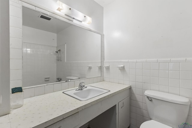 bathroom featuring vanity, toilet, tile walls, and a tile shower