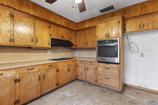 kitchen featuring tasteful backsplash, stainless steel oven, a textured ceiling, ceiling fan, and black gas stovetop