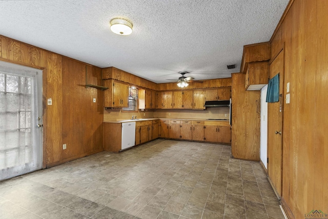 kitchen with wood walls, a textured ceiling, black electric cooktop, white dishwasher, and ceiling fan