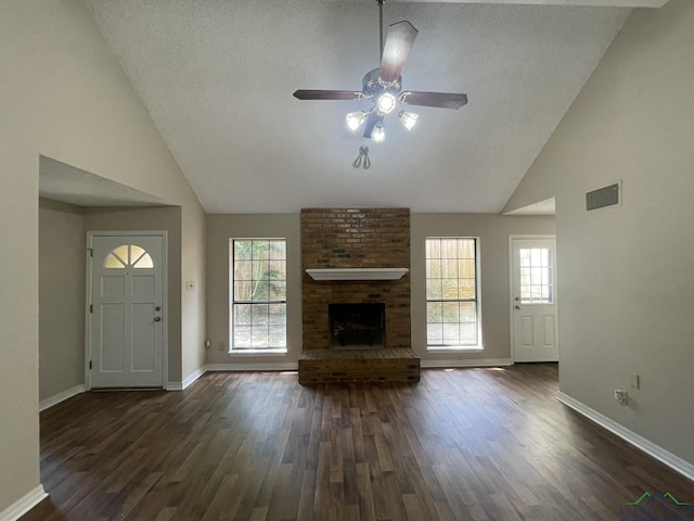 1206 Brandywine Dr, Longview, TX 75601 - unfurnished living room featuring plenty of natural light, dark wood finished floors, high vaulted ceiling, and a textured ceiling