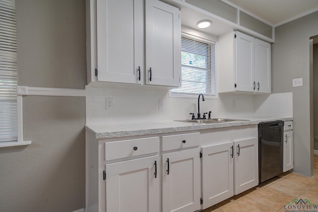 kitchen with tasteful backsplash, sink, light tile patterned floors, white cabinets, and black dishwasher