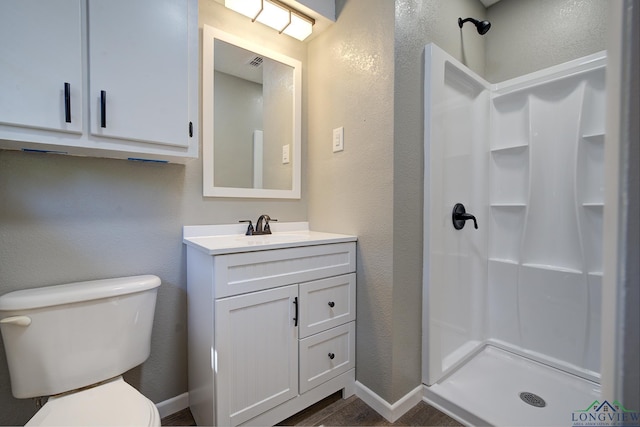 bathroom featuring toilet, a shower, and vanity