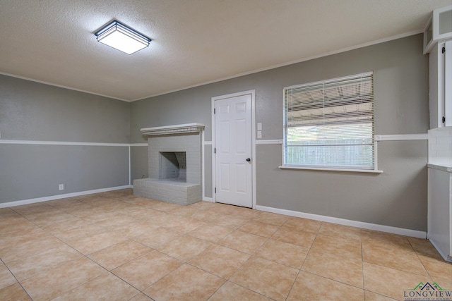 unfurnished living room featuring a fireplace, light tile patterned floors, a textured ceiling, and ornamental molding