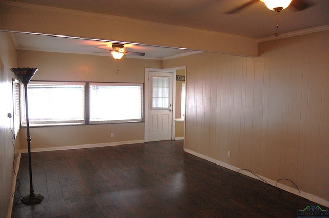 spare room featuring ceiling fan, crown molding, wooden walls, and dark wood-type flooring