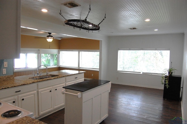 kitchen with white cabinets, a center island, a healthy amount of sunlight, and sink