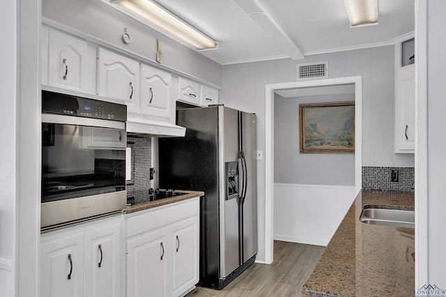 kitchen with appliances with stainless steel finishes, dark stone counters, sink, exhaust hood, and white cabinets