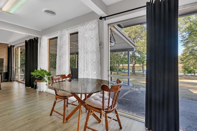 dining space with beam ceiling and light hardwood / wood-style flooring