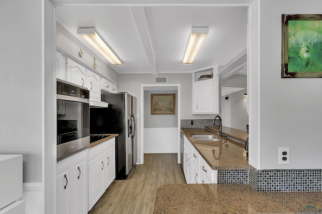 kitchen featuring white cabinets, sink, dark stone countertops, light wood-type flooring, and stainless steel appliances