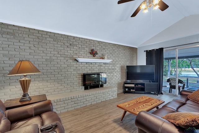 living room featuring ceiling fan, vaulted ceiling, brick wall, and light hardwood / wood-style flooring