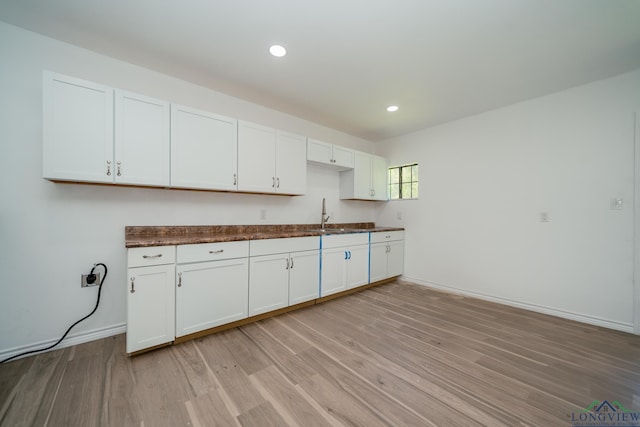 kitchen featuring white cabinetry, sink, and light hardwood / wood-style floors