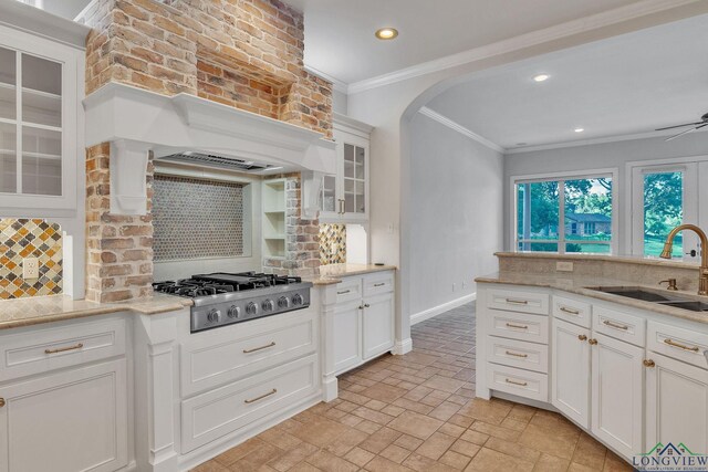 1719 Hg Mosley Pkwy, Longview, TX 75604 - kitchen featuring a sink, stainless steel gas cooktop, tasteful backsplash, crown molding, and arched walkways